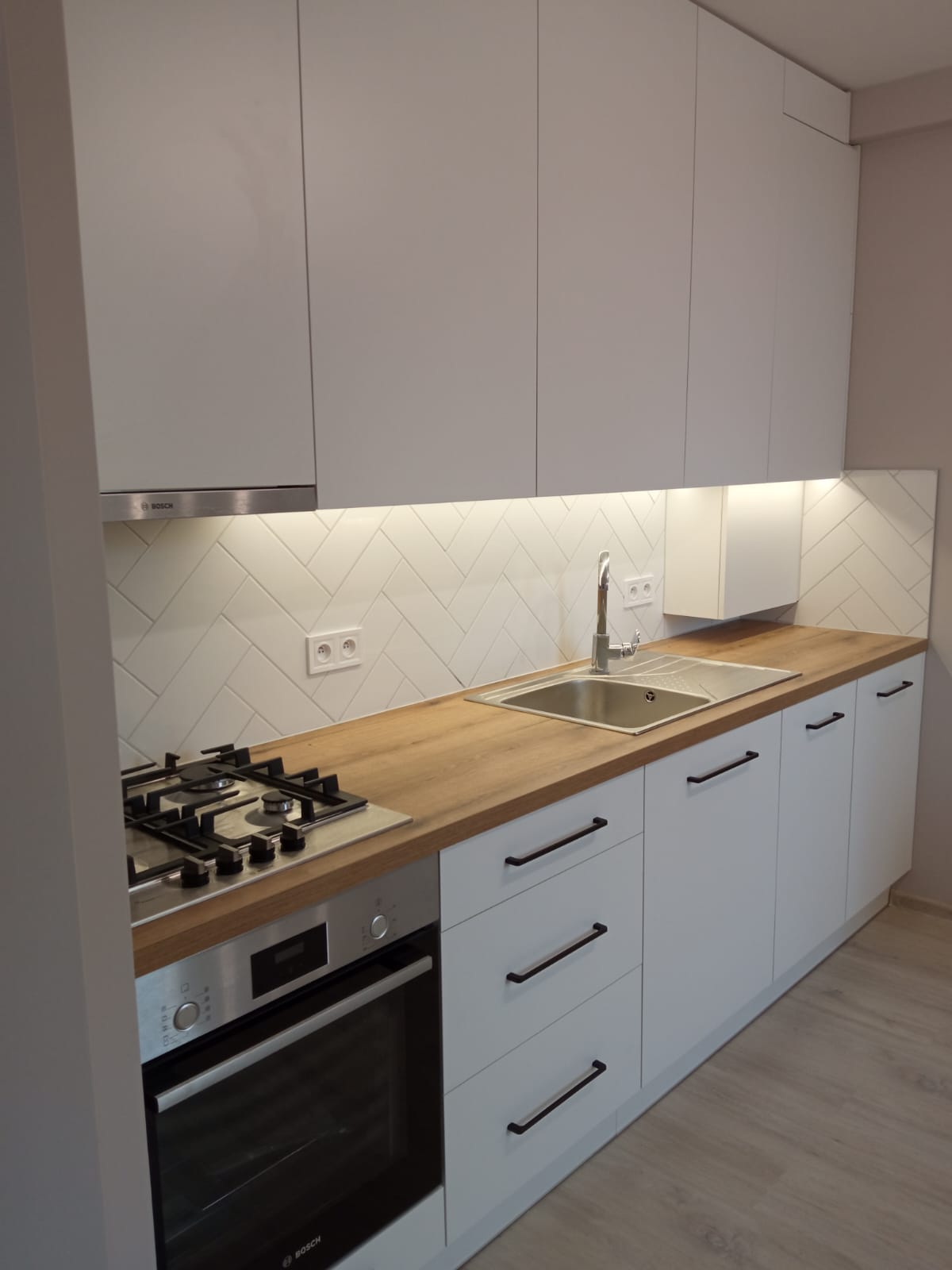 Biała kuchnia skandynawska z drewnianym blatem i jodełką